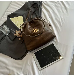 Détail du sac seau vintage marron foncé avec chaîne dorée et cordon de serrage