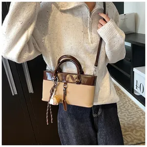 Detail of two-tone mini tote bag with baseball charm on model in casual knitwear