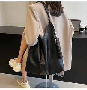 Detailed close-up of large black leather hobo bag with contrast white stitching details