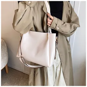 Detailed close-up of cream PU leather tote bag featuring gold hardware and logo engraving