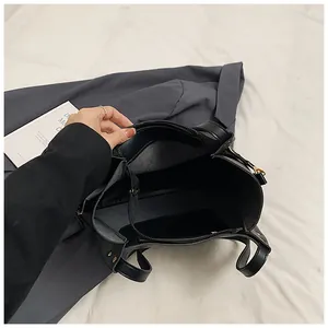 Internal view of black leather tote bag showing spacious multi-layer compartments with gold zipper