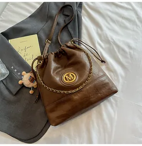 Sac seau vintage marron avec logo M doré et pendentif agneau en peluche sur le côté