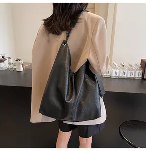 Detailed view of black soft leather tote bag with white contrast stitching and long strap