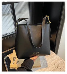 Detail of minimalist black bucket bag with gold lettering and adjustable wide strap