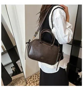 Detailed view of dark brown leather Boston bag with gold hardware and top handle
