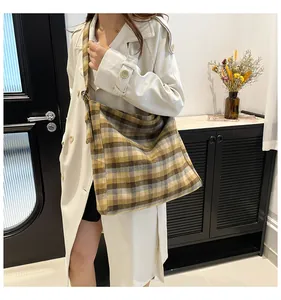 Close-up of a vintage plaid tote bag with a wide strap styled on a white trench coat