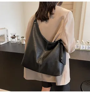 Detail of black leather hobo bag with contrast stitching and soft wrinkled texture