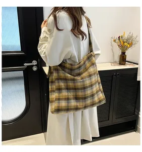 Detail shot of the thick plaid fabric texture on a large yellow and grey tote bag
