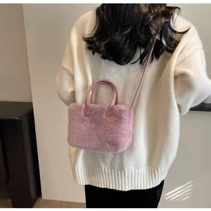 Vue arrière d'un sac à main rose en fausse fourrure porté avec un pull en maille crème