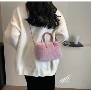 Vue arrière du modèle portant un sac à main en peluche rose avec des poignées en cuir