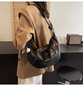 Detail of black hobo bag featuring white contrast stitching and knotted shoulder strap