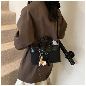Rear view of model wearing a black patchwork tote bag with baseball charm detail