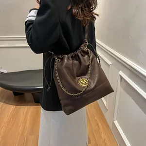 Sac seau en cuir marron pour femme avec logo M doré et bandoulière chaîne pour le bureau