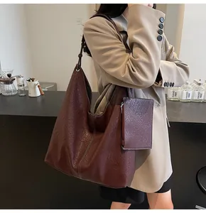 Detail of burgundy soft leather tote bag with white stitching and matching hanging pouch