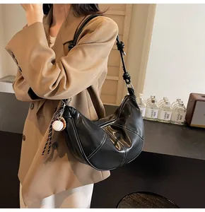 Detail of black crescent hobo bag with white contrast stitching and baseball charm