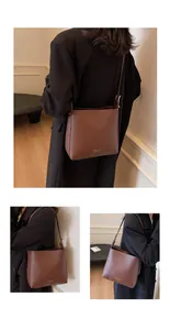 Detail of dark brown leather bucket bag with wide strap and embossed fashion text