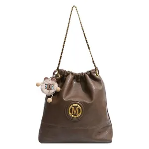 Sac seau marron avec logo M, bandoulière chaîne et pendentif ours pour le quotidien