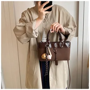 Detail of vintage brown tote bag featuring sport charms and adjustable shoulder strap