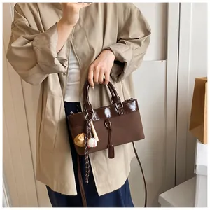 Detailed shot of dark brown tote bag with decorative baseball and wooden bear pendants
