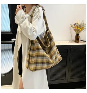 Detail view of large checkered tote bag in brown and yellow woven fabric on model