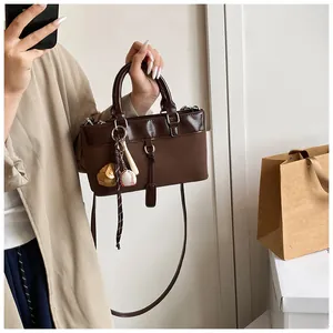 Detail of dark brown tote bag featuring glossy leather texture and baseball glove charm