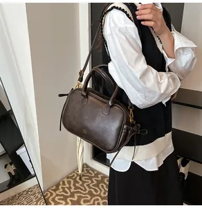 Detailed view of dark brown leather crossbody bag with gold COTH TRM logo and hardware