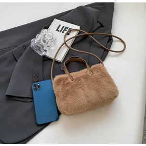 Détail de sac à main en peluche marron avec anse en cuir sur un blazer gris chic