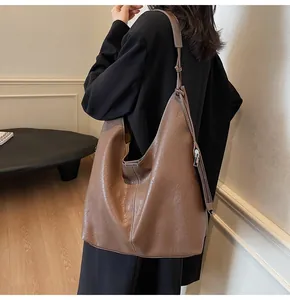 Detailed view of deep brown large leather tote bag with adjustable strap and metal zipper