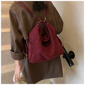 Vista posteriore di una borsa hobo in camoscio bordeaux con doppi spallacci su modella