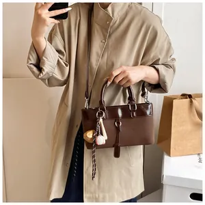 Close-up of vintage brown tote bag with baseball-themed charms and mix of leather textures