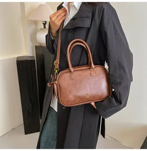 Close-up of a dark brown leather crossbody bag with gold COIN 2DN logo and top handles