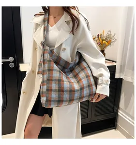 Detail view of plaid tote bag with knotted shoulder strap on a model wearing white coat