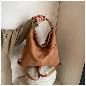 Dettaglio della pelle scamosciata marrone opaca e dei ganci dorati di una borsa moda