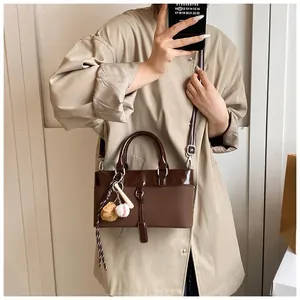 Detail of coffee brown patchwork tote bag featuring baseball leather charm and silver hardware