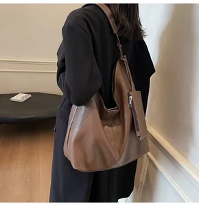 Detail of a large brown hobo tote bag with a small side pouch and white stitching