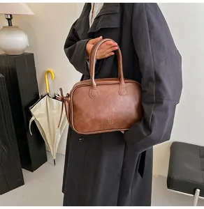 Detail of vintage brown leather Boston bag showing dual handles and secure zip closure