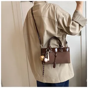 Woman carrying large vintage brown leather tote bag with baseball themed charm details