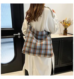 Detail of large plaid tote bag with winter fabric texture worn on model's shoulder