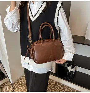 Detailed view of brown leather crossbody bag with top handle and gold-tone hardware