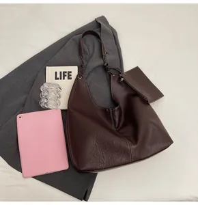 Close-up of soft pleated brown leather tote bag with white contrast stitching and inner pouch