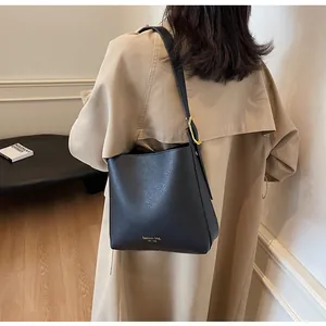 Detail of black matte leather bucket bag with wide shoulder strap and gold hardware