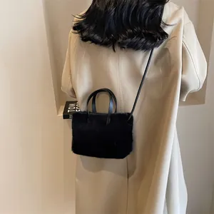 Sac à main chic en peluche noire avec poignées en cuir porté par un mannequin