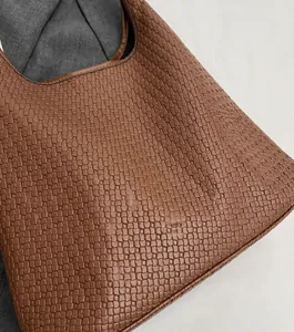 Gros plan sur la texture en cuir tressé marron et la matière souple de ce sac cabas