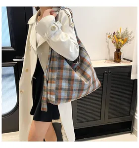 Detail shot of a large plaid tote bag in orange and blue worn with a stylish trench coat