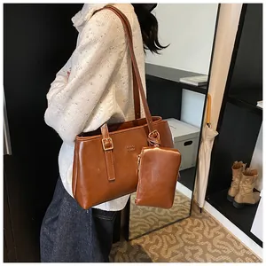 Detail view of brown faux leather tote bag with gold hardware and mini charm pouch