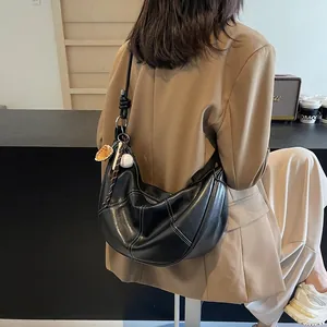 Black crescent croissant bag with white contrast stitching and baseball bag charm