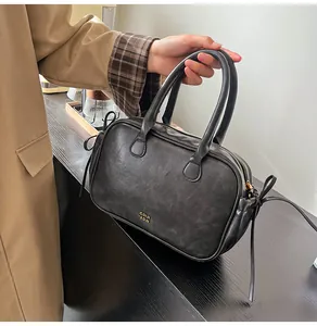 Detail of vintage black leather boston bag featuring gold logo and decorative side bows