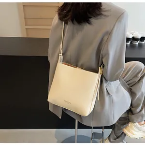Detailed shot of cream white leather shoulder bag worn by model in minimalist indoor setting