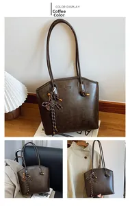 Detailed macro view of dark coffee vintage tote bag featuring textured PU leather and tassel