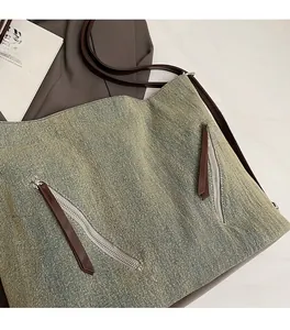 Detail of vintage canvas shoulder bag showing aged texture and dual metal zippers